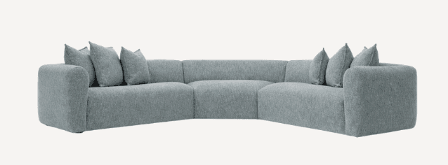A modular sectional sofa with a curved design. The sofa features multiple seating sections and appears to be upholstered in a textured fabric. Several throw pillows are placed on the sofa sections. — 3D model