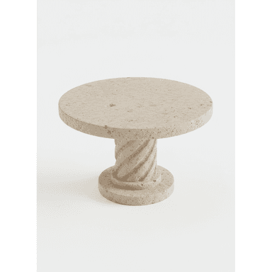 A round, pedestal table with a rough, textured surface. The pedestal has a columnar design with a decorative base and capital, reminiscent of classical architecture. A small, dark ceramic vase with a dried plant is placed on the tabletop. — 3D model