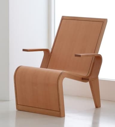 A modern lounge chair constructed from bent plywood, featuring a light wood finish. The design incorporates fluid curves for the seat and backrest, with a distinct, angular base and slender, integrated armrests. The chair exhibits a minimalist and ergonomic form. — 3D model