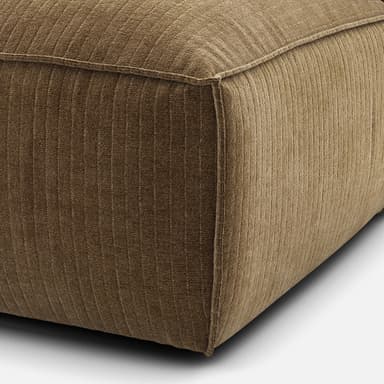 A modular sofa section with a low profile and plush cushioning. It features a single armrest or back support rising vertically from the seat, with a distinct seam line around the perimeter of the base and the seat cushion. The upholstery appears to be a textured fabric with a ribbed pattern. — 3D model