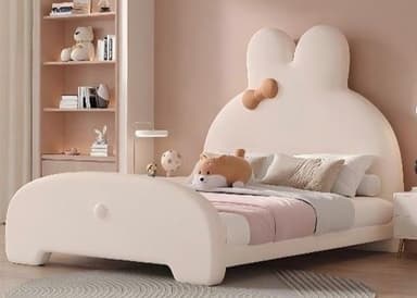 A children's bed with a playful, cartoonish design, featuring a headboard shaped like a rabbit's ears and a decorative bow. The bed frame is low-profile and rounded, with a simple footboard. It is furnished with bedding, including pillows and a blanket, and a small stuffed animal. — 3D model