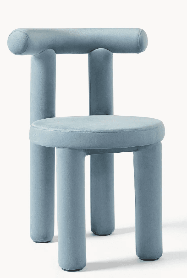 A contemporary armless chair featuring a distinctive design composed entirely of upholstered, cylindrical forms. The chair is covered in a soft, light blue velvet fabric, giving it a plush appearance. It consists of a round seat supported by four thick, cylindrical legs. The backrest is formed by two shorter vertical cylindrical posts that connect to a single horizontal cylindrical bar, creating a unique, rounded silhouette. The overall aesthetic is minimalist yet playful, with smooth curves and a monochromatic finish. — 3D model