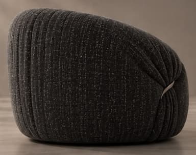 A contemporary, generously padded armchair with a sculptural and organic form, upholstered in a dark charcoal grey fabric with subtle white flecks. The chair features a rounded, low-slung profile and distinct pleating or gathering of the fabric, particularly evident around the armrests and base, giving it a plush, cloud-like appearance. A single, sleek silver-toned metal ring acts as a decorative and structural detail on one side, cinching the upholstery. — 3D model