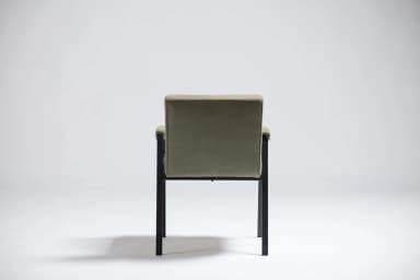 An armchair with a dark-colored frame and upholstered seat, back, and armrests in a light olive green fabric. The frame appears to be made of metal or a dark wood, with slender legs and arm supports. The upholstery has a textured weave. The design suggests a mid-century modern or contemporary aesthetic. — 3D model