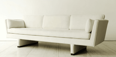 A contemporary three-seater sofa upholstered in an off-white bouclé-like fabric, featuring a single button-tufted seat cushion, three loose back cushions, and integrated wide arms resting on a recessed, block-like base. — 3D model