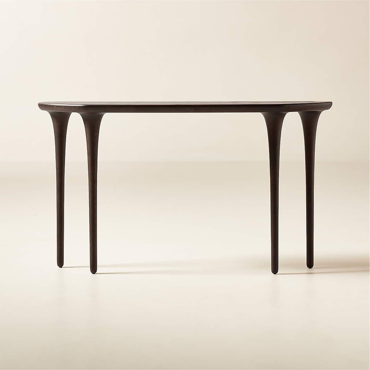 A dark-toned console table featuring a subtly curved rectangular top and four distinctive, sculptural legs. The legs are integrated into the tabletop with a gentle flare and taper downwards, giving the table an elegant and contemporary appearance. The overall finish is a deep, rich brown, almost black, suggesting either a dark wood or a heavily stained material. — 3D model