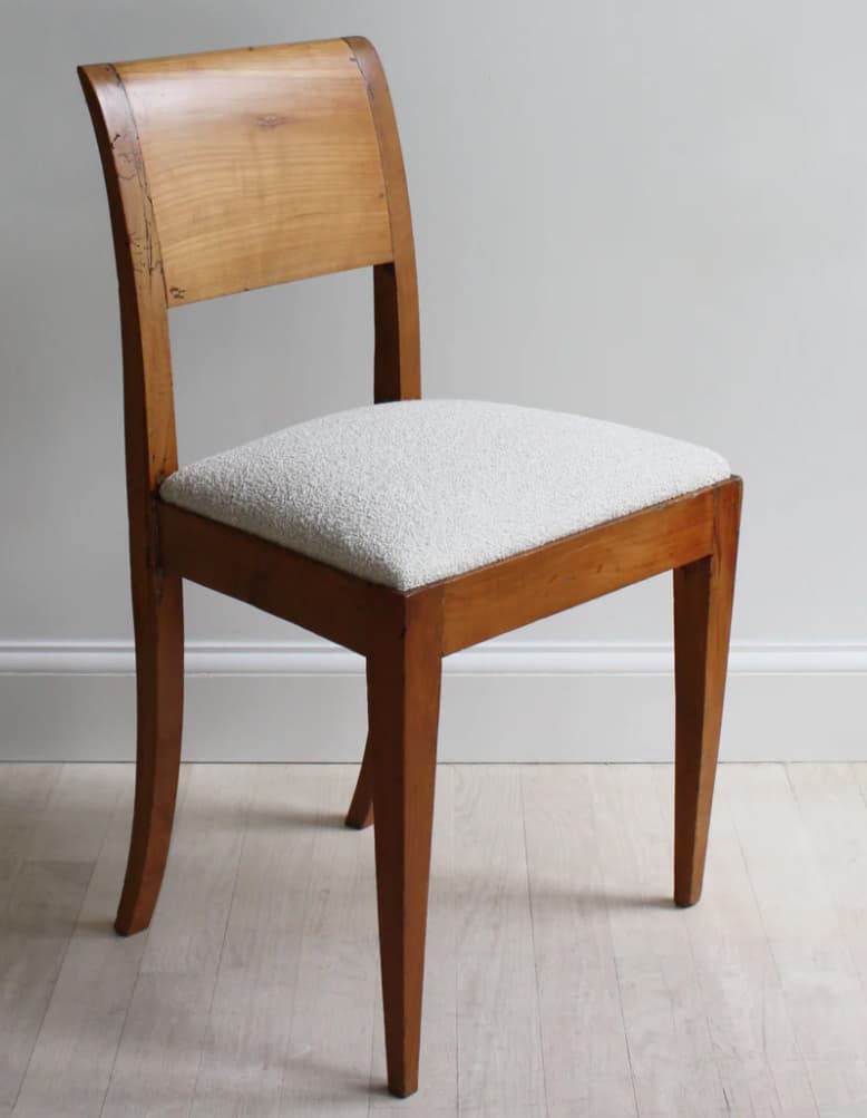 A wooden chair with a curved backrest and a upholstered seat. The chair has four legs, with the front legs tapering towards the floor and the back legs having a subtle curve. — 3D model
