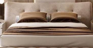 A modern platform bed featuring a generously upholstered headboard in a neutral beige fabric. The headboard is subtly curved and includes button tufting, adding a touch of classic detail. The bed frame itself is a low-profile platform design, complementing the clean lines of the headboard. The bed is dressed with bedding in shades of cream and brown, including two large brown pillows and a cylindrical pillow. — 3D model