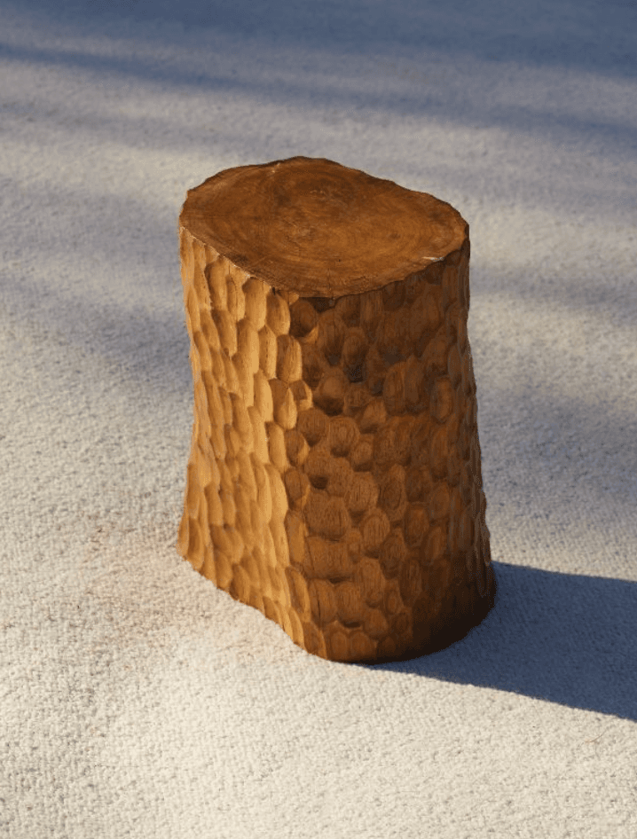 A compact, solid wood side table featuring a distinctive hand-carved, textured surface on its cylindrical body and a smooth, flat top, revealing the natural wood grain. The carving gives it an organic, chiseled appearance. — 3D model