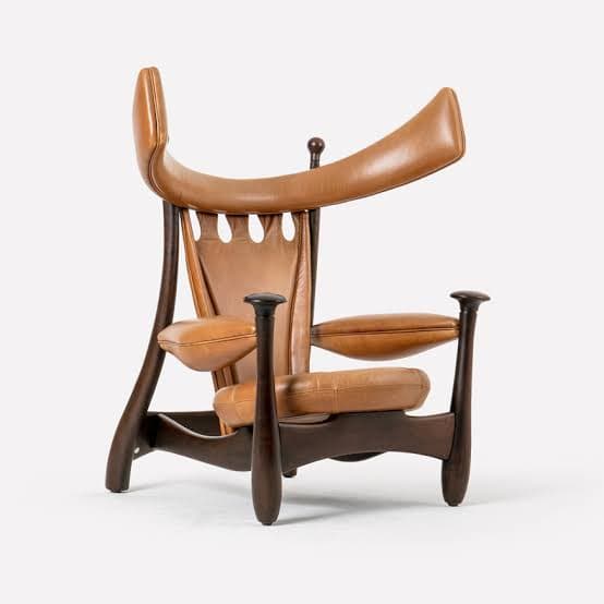 A distinctive lounge chair featuring a sculptural dark-stained wooden frame and light brown leather upholstery. The backrest is high and dramatically curved, offering a unique silhouette. The seat and armrests are padded with the same tan leather, integrating seamlessly into the robust wooden structure. The design emphasizes organic forms and a robust, yet elegant, presence. — 3D model
