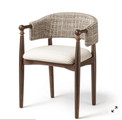 An elegantly designed contemporary armchair featuring a dark, rich wooden frame, possibly walnut. The chair includes a generously padded seat upholstered in a light beige or off-white fabric with subtle horizontal pinstripes. Its most distinctive feature is the curved, wrap-around backrest, which integrates into short armrests. The backrest is upholstered in a textured, woven fabric with a mottled brown and beige pattern, resembling tweed or bouclé. The armrests are capped with spherical wooden finials. The four legs are slender and tapered, contributing to the chair's refined aesthetic. — 3D model
