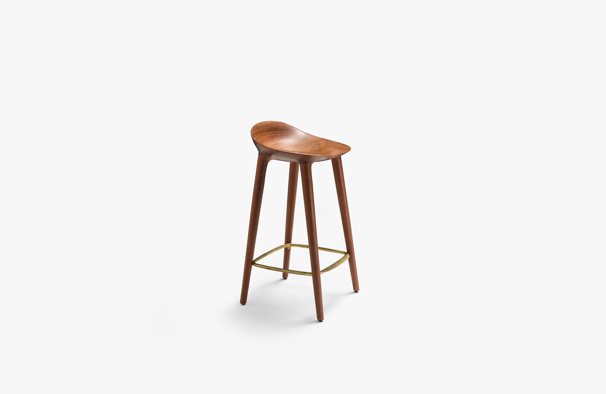 A modern bar stool crafted from dark brown wood, likely walnut, featuring a deeply sculpted saddle seat for ergonomic comfort. It stands on four slender, tapered legs that splay slightly outwards, connected by a triangular brass-toned metal footrest. The design is minimalist and contemporary, highlighting the natural beauty of the wood grain. — 3D model