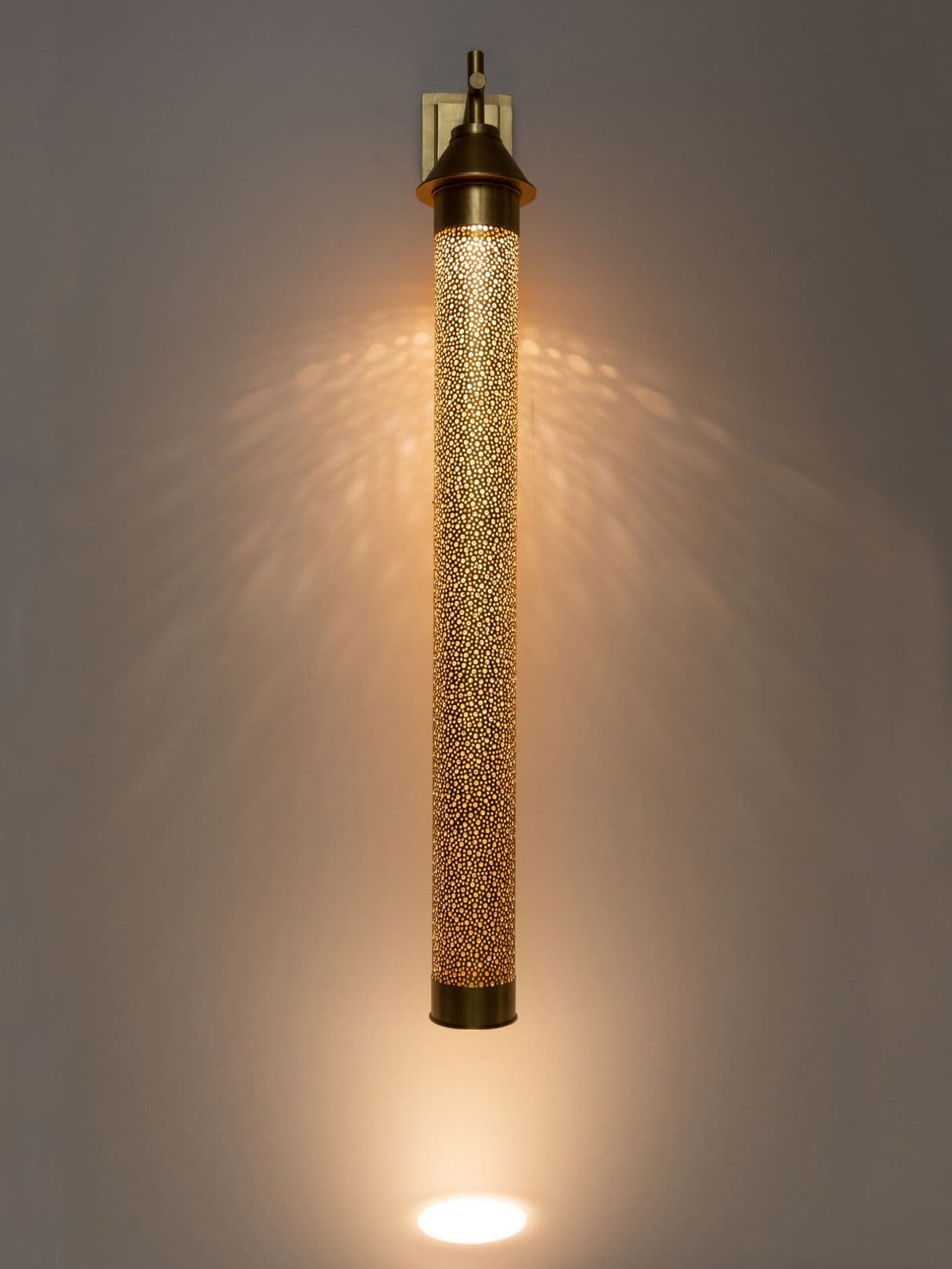 A decorative wall sconce featuring a cylindrical shade with a perforated pattern, mounted on a square backplate with a decorative cap. — 3D model