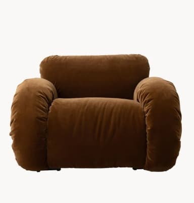 A plush, sculptural armchair upholstered in a rich brown velvet fabric. The armchair features an organic, rounded silhouette with ample cushioning that appears to be gathered or shirred, creating a textured effect. A tubular metal frame, finished in a light, possibly cream or off-white color, is visible beneath the upholstery, providing structural support and a contrasting element. The design evokes a contemporary, possibly retro-inspired aesthetic. — 3D model