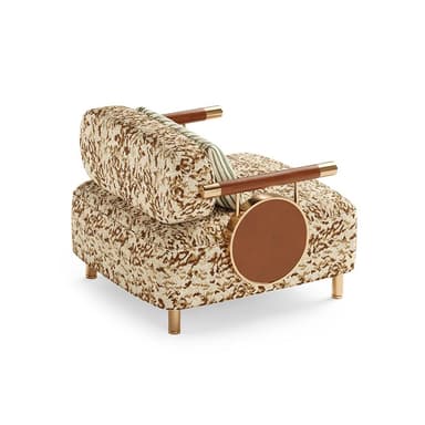 An avant-garde accent armchair featuring a patterned fabric upholstery in shades of beige and brown, lending an eclectic and luxurious aesthetic. The chair incorporates unique armrests made of polished brass rods wrapped with brown leather, which extend to support a circular, integrated side table on one side, also finished in brown leather and framed in brass. It is supported by four slender, tapered brass legs, suggesting a modern yet opulent design. — 3D model