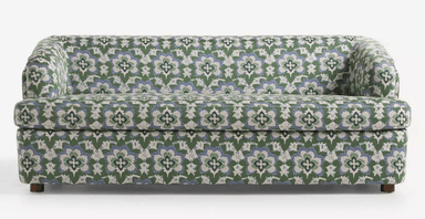 A three-seater sofa with a rounded armrest on the left side. The sofa is upholstered in a fabric with a repeating floral pattern in green, blue, and white. It has a solid base and short, wooden legs. — 3D model