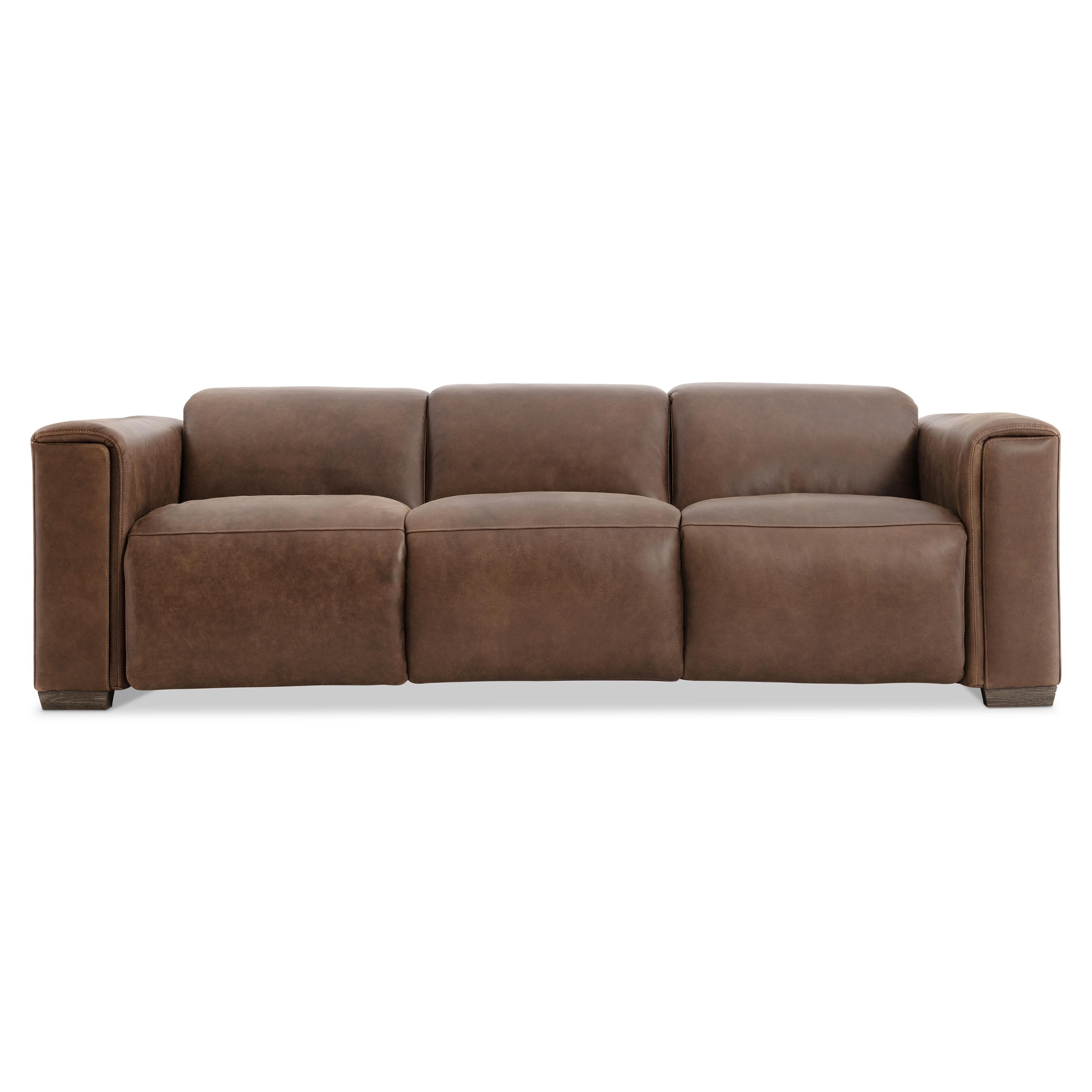 A modern three-seater sofa upholstered in rich brown leather, featuring clean lines and a minimalist aesthetic. The sofa has a solid back with three individual back cushions and three seat cushions, providing ample seating. The arms are wide and block-like, extending to the front, and the sofa rests on short, rectangular wooden block feet. — 3D model