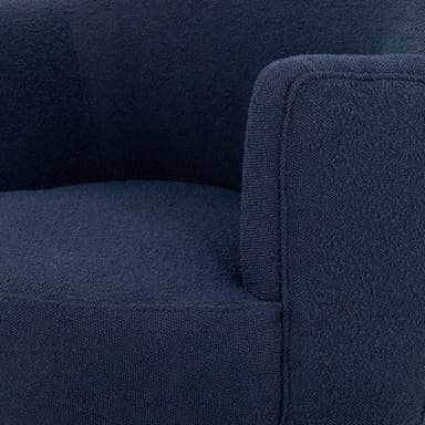 A contemporary armchair upholstered in a textured navy blue fabric. It features a rounded back and integrated armrests that curve gently downwards. The chair is supported by a circular, dark wood swivel base, allowing for 360-degree rotation. The upholstery has a boucle or similar textured finish. — 3D model