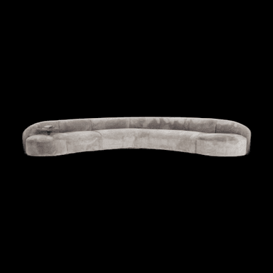 A long, curved sofa with a plush, textured upholstery. The sofa features a continuous, rounded backrest and seat. On the left side of the sofa, a small, integrated side table or armrest extension with a wooden top is visible. The overall form is modern and organic. — 3D model