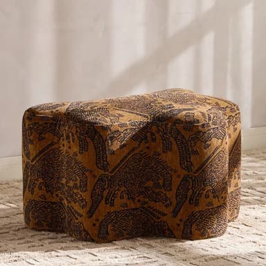 A plush, organically shaped ottoman, upholstered in a brown fabric with a dark, intricate tribal or animalistic pattern. Its base has a distinct wavy, undulating form, and it appears to be entirely covered in the same material without exposed legs. — 3D model