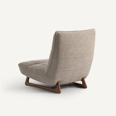 A modern armchair with a low profile and a sloped backrest. The armchair features upholstered seating and back cushions with subtle tufting. It is supported by a minimalist wooden base with angled legs. — 3D model
