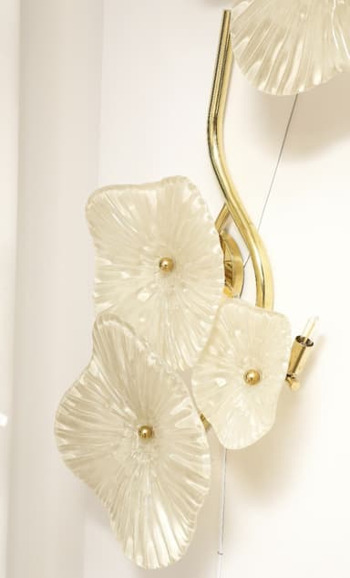 A decorative chandelier featuring multiple floral-shaped diffusers made of textured, translucent material, attached to a brass-finished metal frame that appears to mimic organic growth, resembling a vine or branch. Each diffuser has a central golden embellishment and exhibits radial fluting for light diffusion. The overall design evokes a whimsical and artistic aesthetic, suitable for ambient or decorative lighting. — 3D model