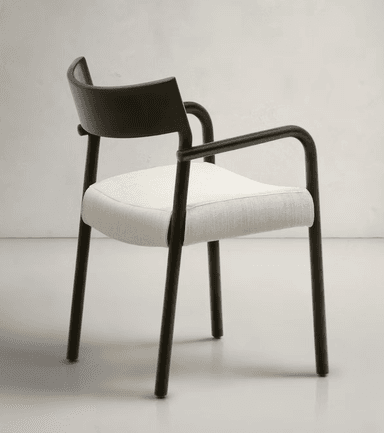 A modern armchair featuring a dark, matte-finished frame with a curved backrest and arms. The seat is upholstered in a light-colored, textured fabric. The legs are slender and cylindrical, matching the frame's finish. The design emphasizes clean lines and a minimalist aesthetic. — 3D model