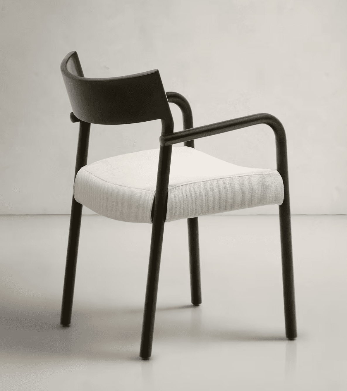 A modern armchair featuring a dark, matte-finished frame with a curved backrest and arms. The seat is upholstered in a light-colored, textured fabric. The legs are slender and cylindrical, matching the frame's finish. The design emphasizes clean lines and a minimalist aesthetic. — 3D model