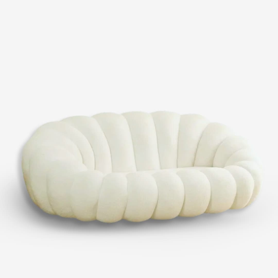 A low-profile, cream-colored upholstered loveseat featuring a distinctive channeled or 'bubble' design. The seating unit consists of deeply cushioned, rounded segments that form the backrest, arms, and seat, creating a continuous, organic form. The absence of visible legs gives it a grounded appearance. — 3D model