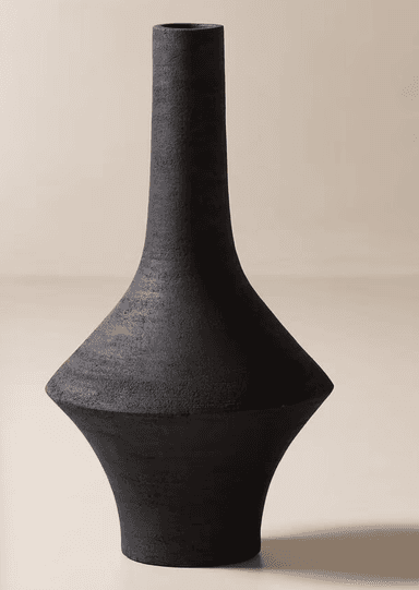 A tall, black decorative vase with a geometric and sculptural form. It features a narrow, cylindrical neck that flares out dramatically into a wide, sharp-angled body, then tapers towards a stable base. The vase has a matte, textured finish, suggesting a ceramic or stoneware construction. — 3D model