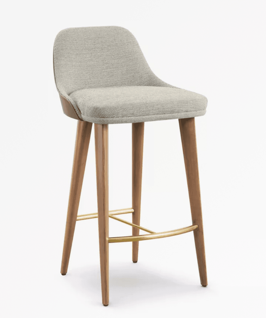 A contemporary bar stool featuring a light grey upholstered seat and low back, supported by four tapered wooden legs with polished brass footrests. — 3D model