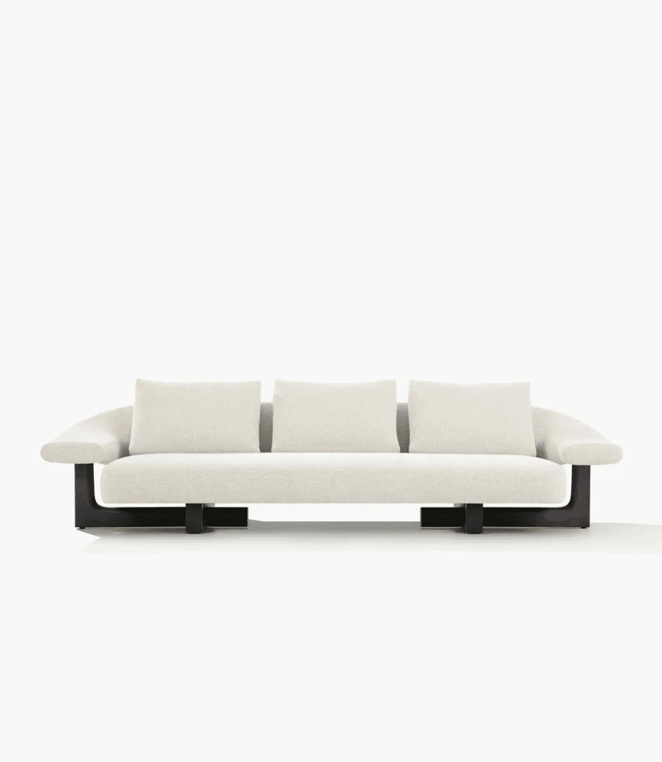 A modern three-seater sofa featuring a clean, minimalist design. It has cream or off-white textured fabric upholstery, comprising a single integrated seat cushion and three loose rectangular back cushions. The sofa is supported by a distinctive dark, exposed rectangular base that extends from the floor upwards, creating a floating effect for the main upholstered body. The arms are wide and gently curved, integral to the main frame. — 3D model