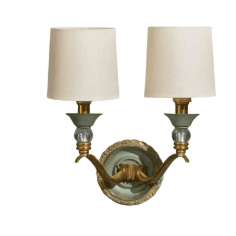 A traditional two-light wall sconce featuring a light green and gold ornate backplate, curved brass arms, crystal sphere accents, and tapered cream fabric shades. — 3D model