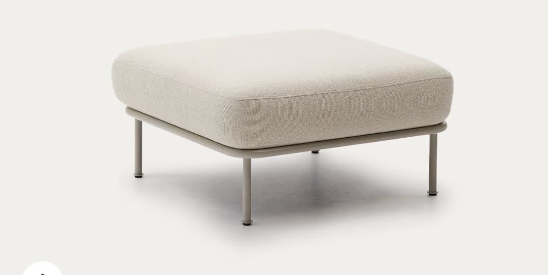 A modern square ottoman featuring a generously cushioned top upholstered in a light beige, subtly textured fabric. The cushion exhibits softly rounded edges, contributing to a contemporary aesthetic. It is supported by a slender, painted grey metal frame with four slim, cylindrical legs, elevating the upholstered body slightly off the ground. The design is minimalist and functional. — 3D model
