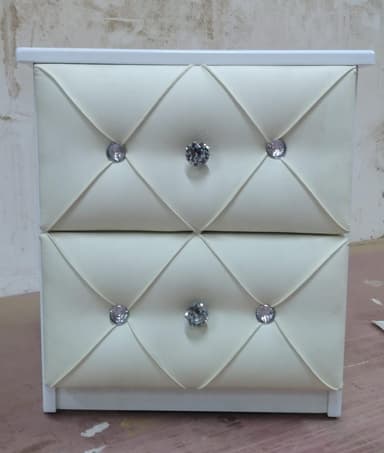 A two-drawer nightstand with a white frame and cream-colored upholstered drawer fronts featuring tufting and crystal-like drawer pull knobs. — 3D model