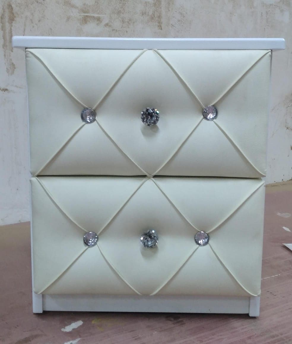 A two-drawer nightstand with a white frame and cream-colored upholstered drawer fronts featuring tufting and crystal-like drawer pull knobs. — 3D model