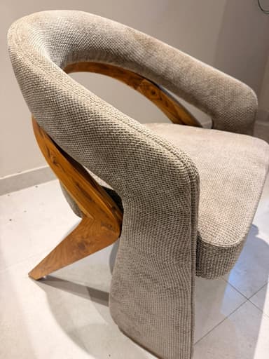 A contemporary armchair with a curved backrest and upholstered seat and arms. The frame appears to be constructed from wood, visible as a curved piece supporting the backrest. The upholstery is a textured fabric in a neutral tone. — 3D model