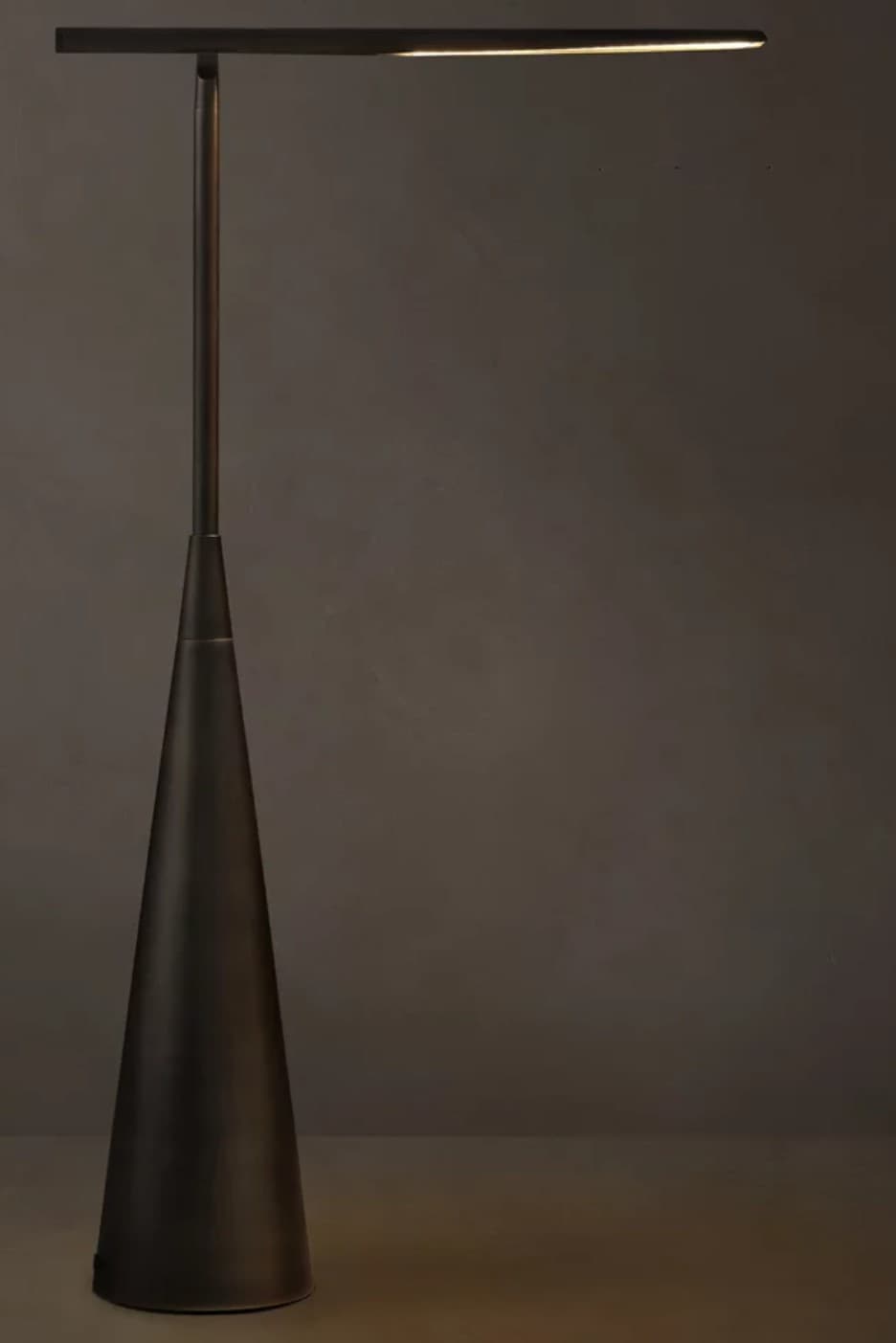 A modern floor lamp featuring a slender, dark metallic pole rising from a wide, inverted conical base. The top terminates in a horizontally oriented, rectangular light bar that emits a warm white light, indicative of an integrated LED strip. The design is minimalist and sleek. — 3D model