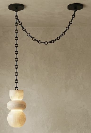 A contemporary pendant light featuring a sculptural shade crafted from translucent alabaster, suspended by a black metal chain system. The shade is composed of three stacked, organic, rounded forms, illuminated from within to highlight the natural veining and luminous quality of the stone. The suspension system consists of a long chain dropping from one ceiling mount, connecting to the light fixture, and a shorter chain extending horizontally to a second ceiling mount, creating a distinctive draped effect. — 3D model