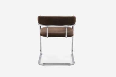 A modern armchair featuring a cantilevered tubular chrome frame and dark brown fabric upholstery. The seat and backrest are integrated, with the back curving upwards and outwards to form armrests. — 3D model