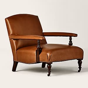 A traditional armchair upholstered in rich brown leather, featuring turned wooden front legs and arm supports, and accented with visible nailhead trim. — 3D model