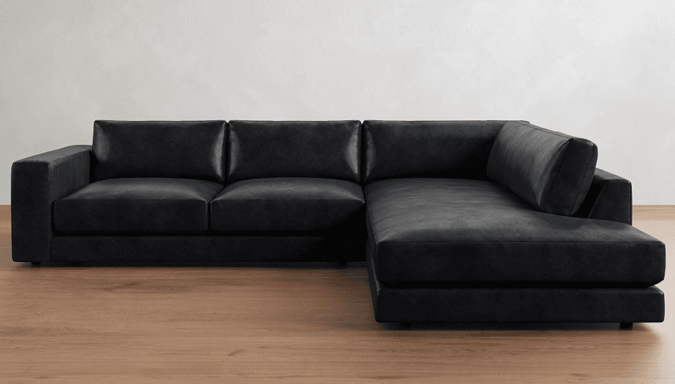 A modern, large black sectional sofa upholstered in what appears to be leather or high-quality faux leather. It features a clean, blocky silhouette with wide track arms and loose back and seat cushions. The sectional includes a prominent right-hand facing chaise lounge extension, providing ample seating and lounging space. The sofa rests on low-profile, recessed feet. — 3D model