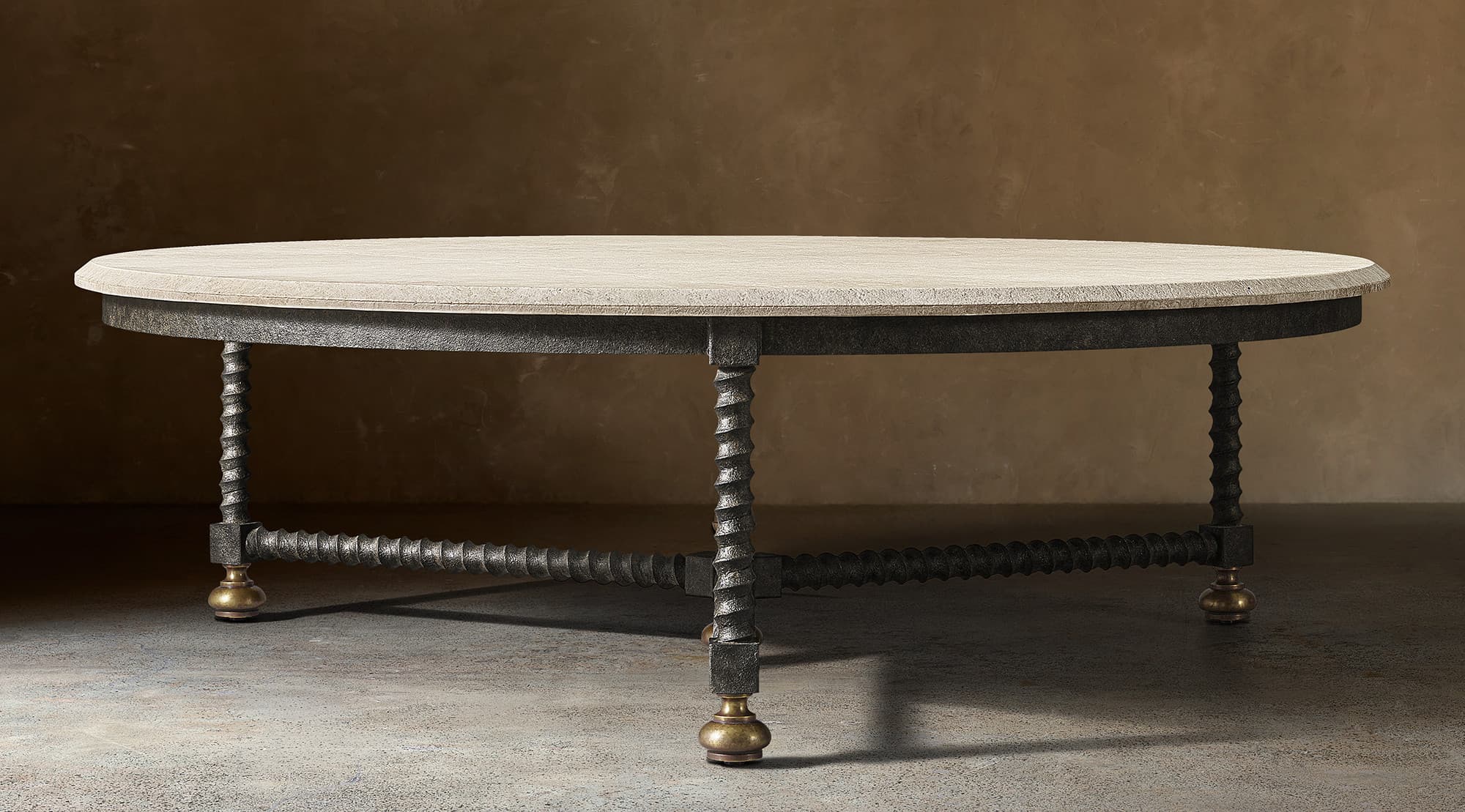 An oval coffee table featuring a light-colored, rough-hewn stone tabletop. The base consists of a dark, textured metal frame supporting four barley-twist style legs, which are interconnected by a stretcher of similar twisted design. Each leg terminates in a spherical brass foot. The overall aesthetic is rustic and traditional. — 3D model