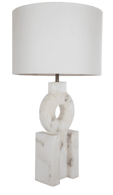 A modern table lamp featuring a sculptural, geometric base crafted from white onyx with subtle brown veining, topped by a classic white drum shade. The base consists of rectangular blocks supporting a central ring shape with a void, creating an abstract, architectural aesthetic. — 3D model