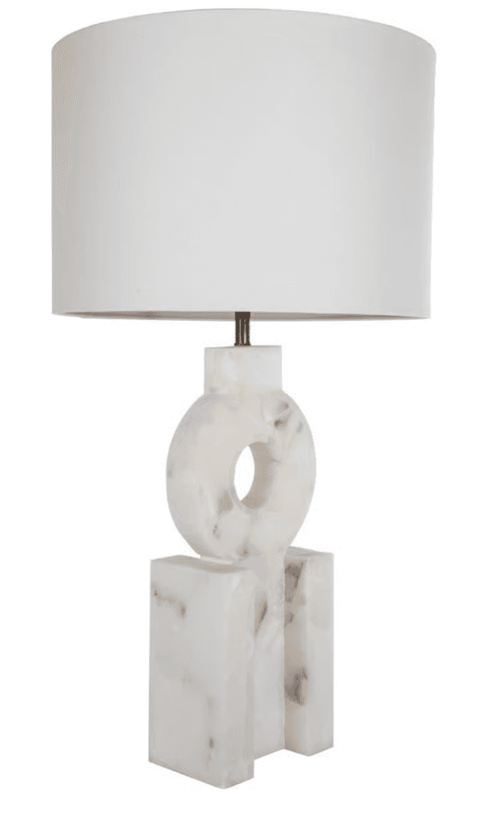 A modern table lamp featuring a sculptural, geometric base crafted from white onyx with subtle brown veining, topped by a classic white drum shade. The base consists of rectangular blocks supporting a central ring shape with a void, creating an abstract, architectural aesthetic. — 3D model