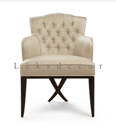 An elegant, cream-colored upholstered armchair featuring classic design elements. The chair has a gently curved, scalloped backrest adorned with deep button tufting. Its armrests are fully upholstered, providing a comfortable feel. The seat is also upholstered in the same patterned cream fabric. The chair is supported by four dark wood tapered legs, with the front two legs connected by a distinctive X-shaped stretcher near the floor. — 3D model