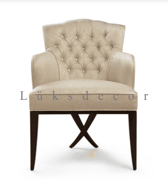 An elegant, cream-colored upholstered armchair featuring classic design elements. The chair has a gently curved, scalloped backrest adorned with deep button tufting. Its armrests are fully upholstered, providing a comfortable feel. The seat is also upholstered in the same patterned cream fabric. The chair is supported by four dark wood tapered legs, with the front two legs connected by a distinctive X-shaped stretcher near the floor. — 3D model