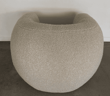 A rounded armchair with a plush, textured upholstery. The armchair features a deep seat and a wraparound backrest that seamlessly integrates into the armrests. The texture appears to be a boucle or similar looped fabric, giving it a soft and inviting appearance. — 3D model