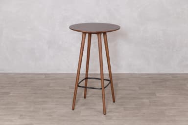 A tall, round bar table featuring a dark walnut-finished tabletop supported by three splayed wooden legs, which are reinforced and connected by a black metal ring footrest. — 3D model