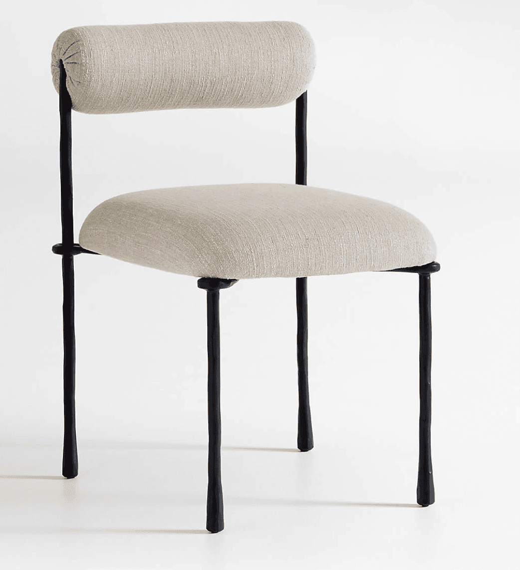 A modern armless chair featuring a dark-colored metal frame with an organic, somewhat irregular texture. It has a light beige or off-white upholstered seat cushion and a cylindrical, bolster-style backrest, also upholstered in the same fabric. The chair stands on four slender, tapered legs. — 3D model